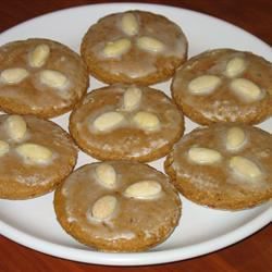 round ginger cookies decorated with three blanched almonds and a thin lemon glaze, arranged on a white plate