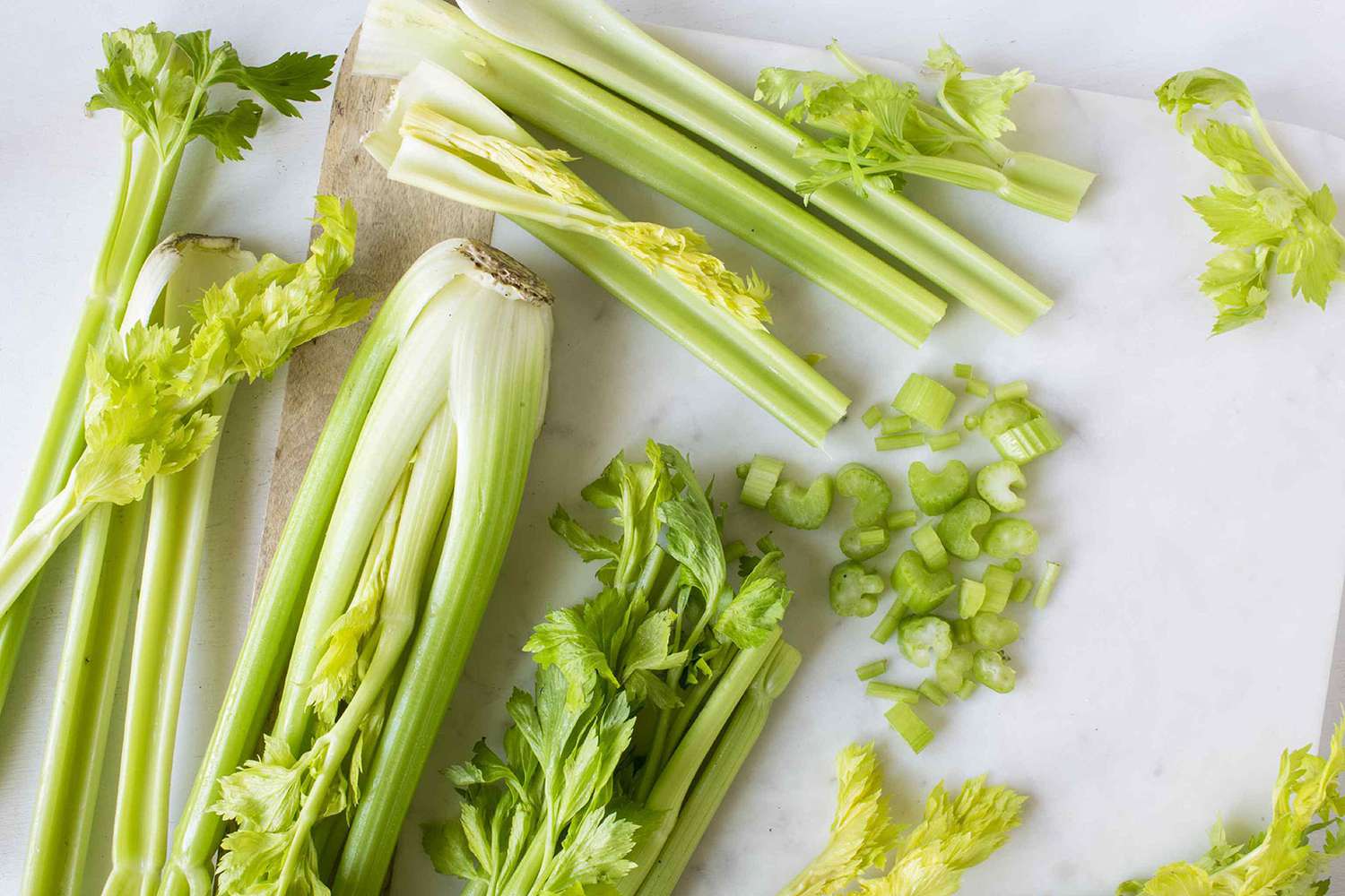 Whole celery, celery stalks, and chopped celery on marble