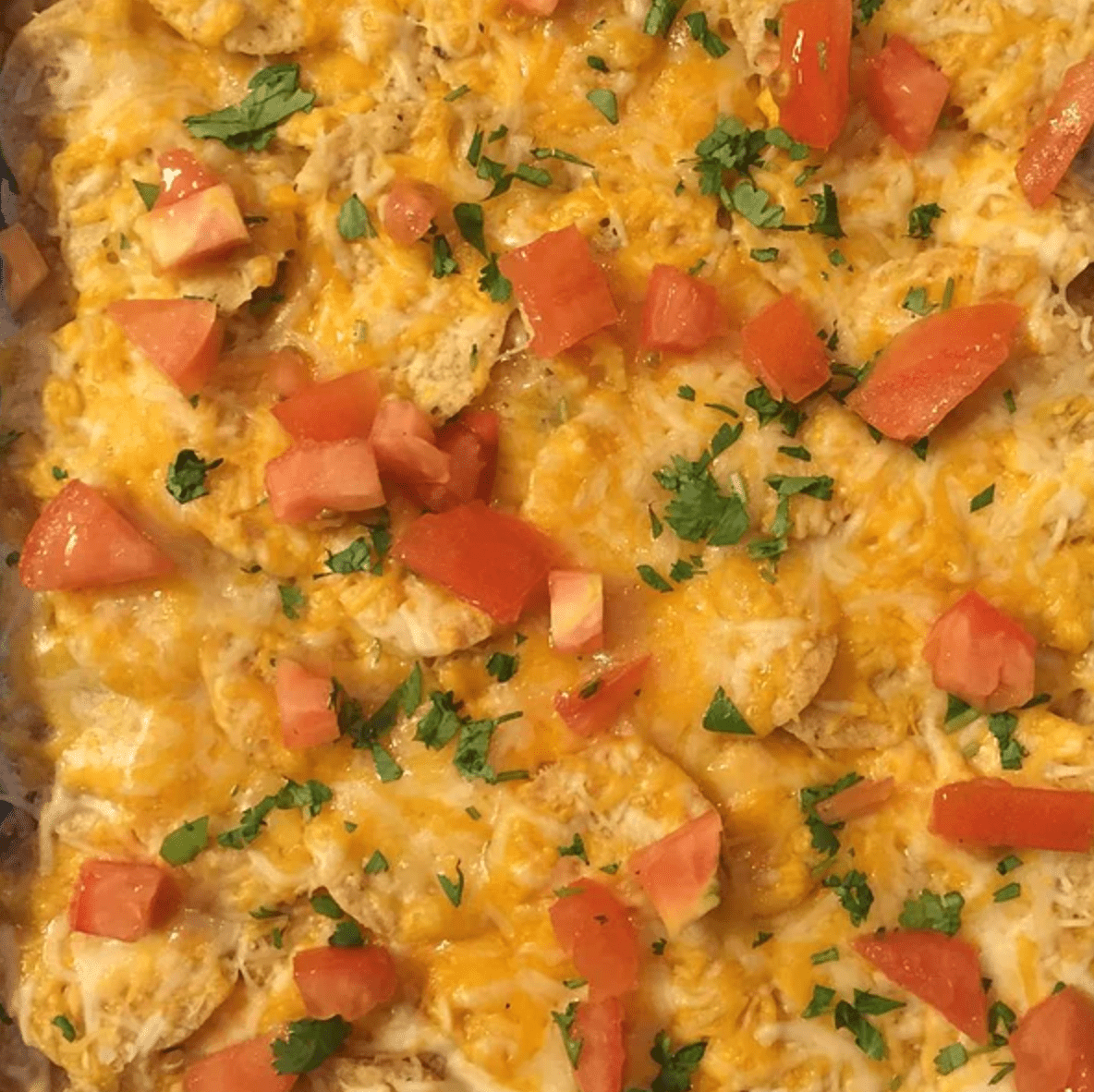 close up of cheesy chicken and chip casserole with tomatoes and green onions