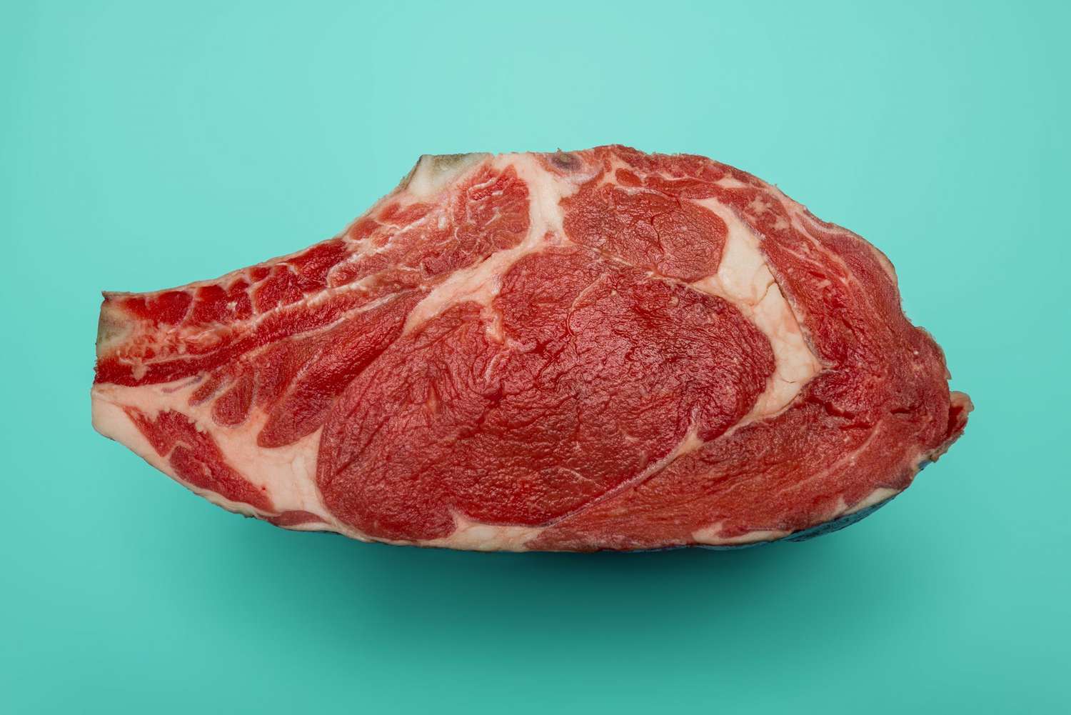 Raw steak on teal backdrop