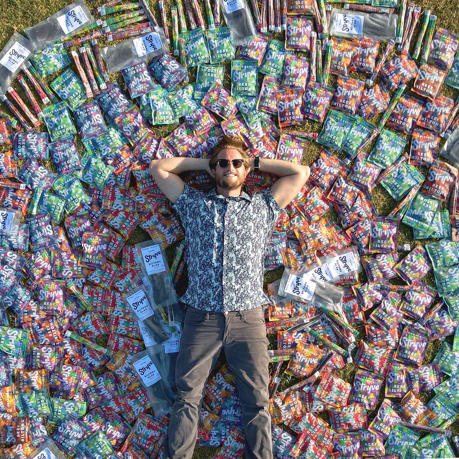 man laying in a field surrounded by packaged jerky