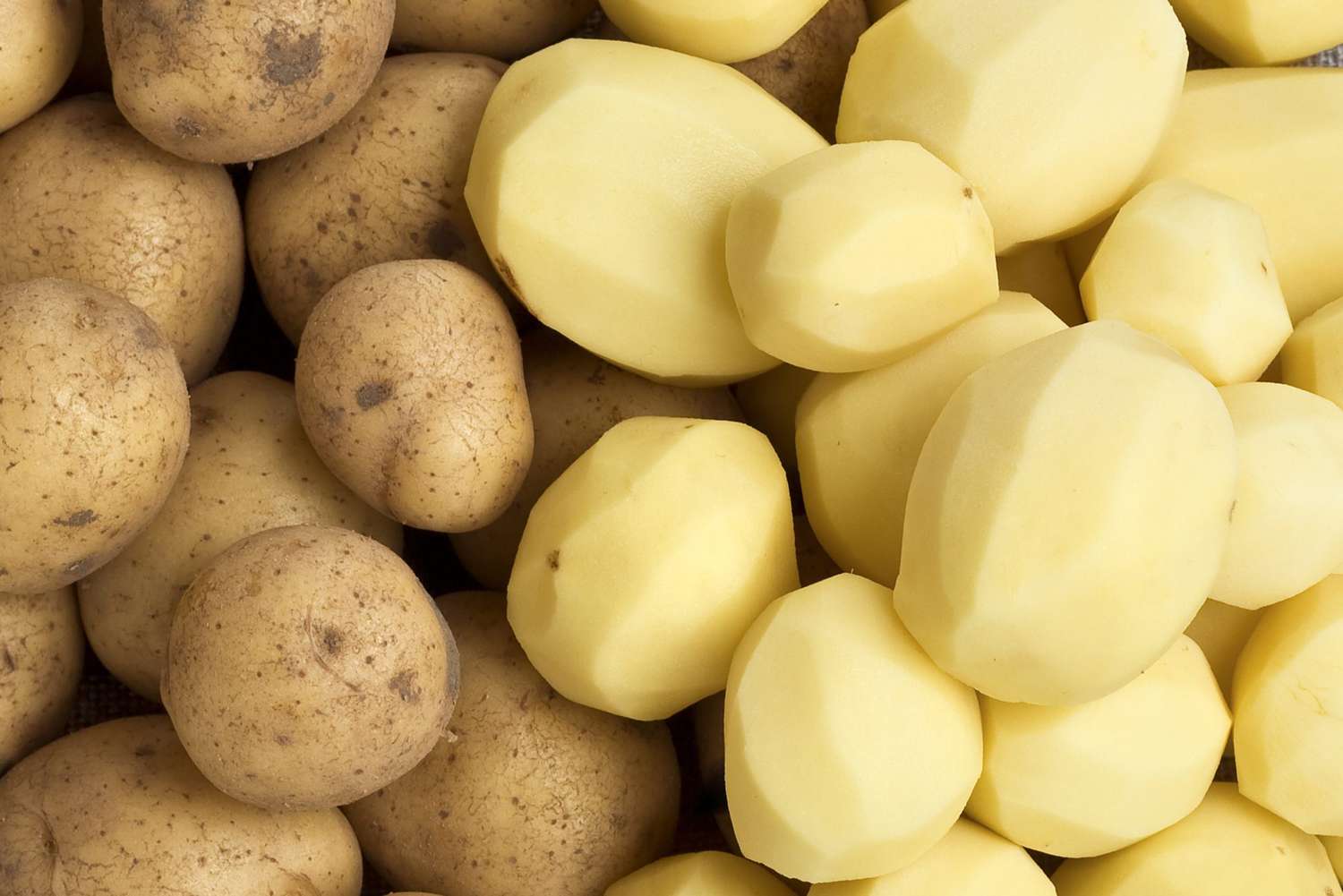 Raw potatoes next to peeled potatoes