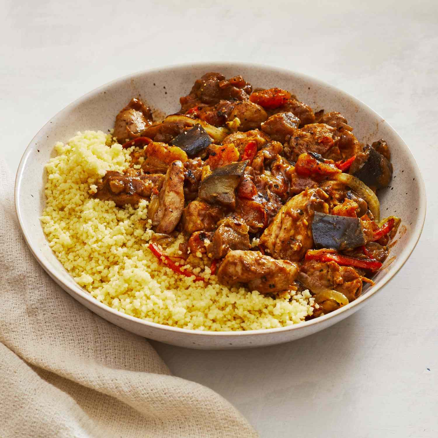 A shallow bowl of chicken tagine with couscous.