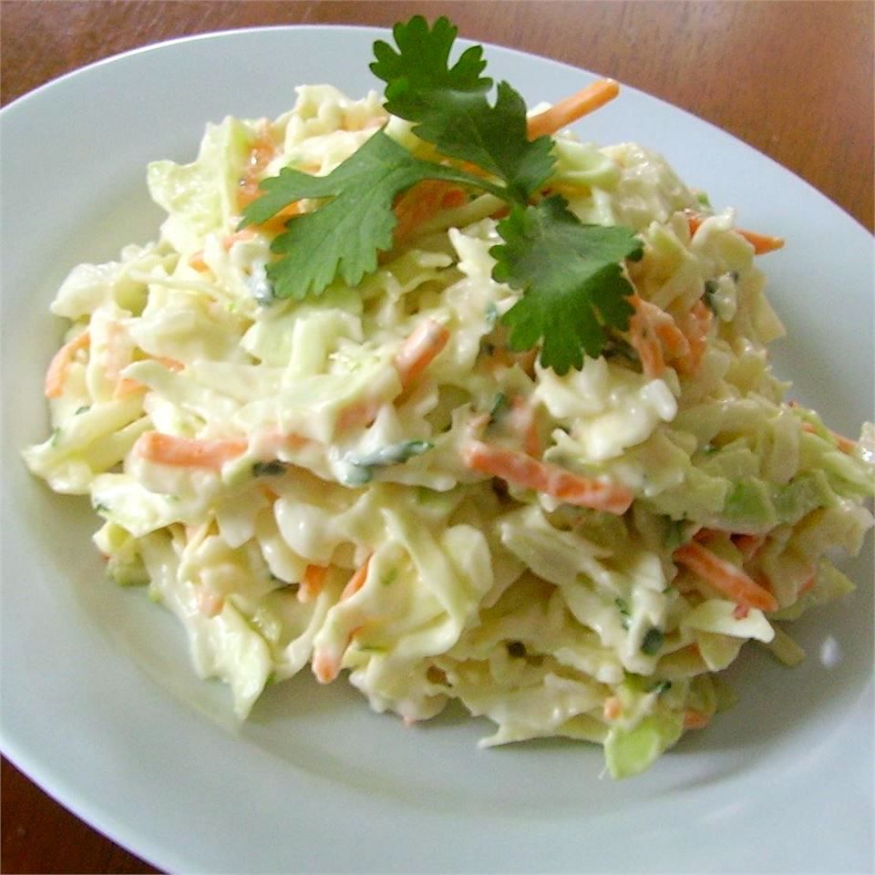 a serving of green cabbage coleslaw garnished with cilantro on a white plate