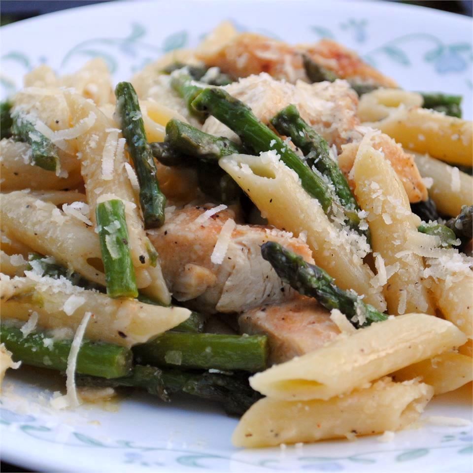 chicken and asparagus penne pasta on a white plate