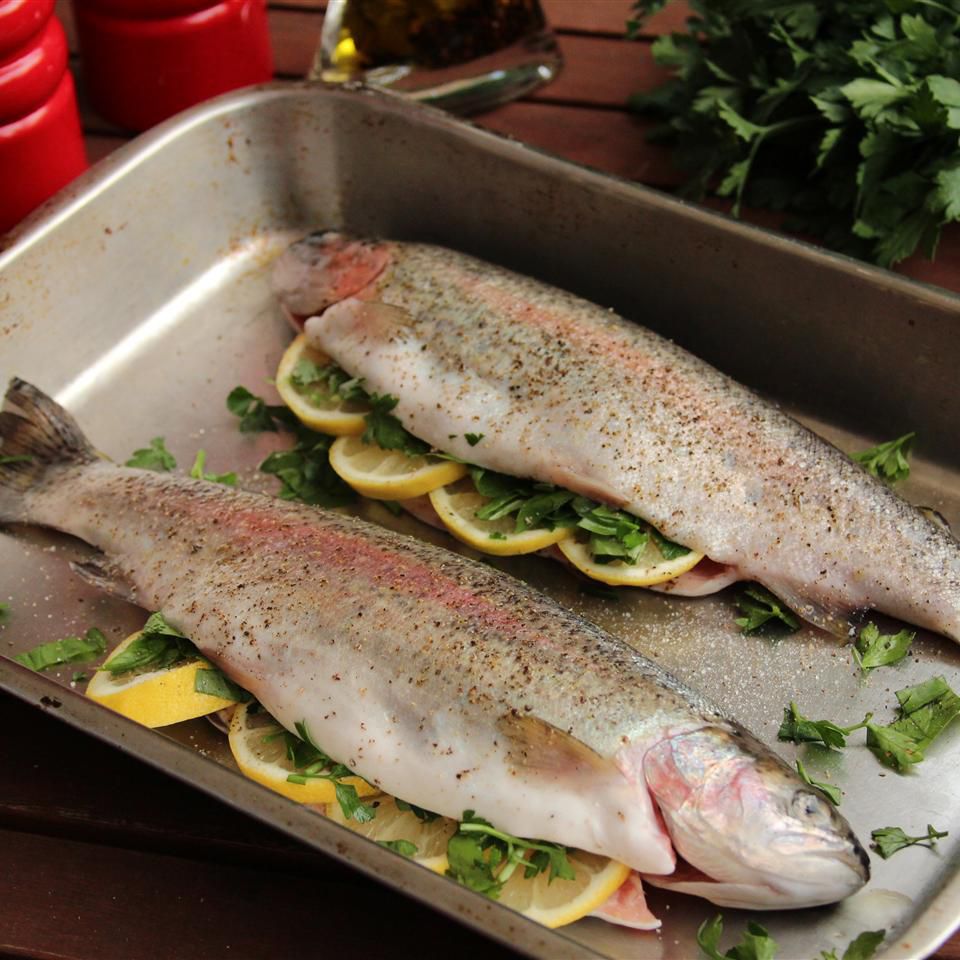 two whole rainbow trouts on a pan with lemon and herbs