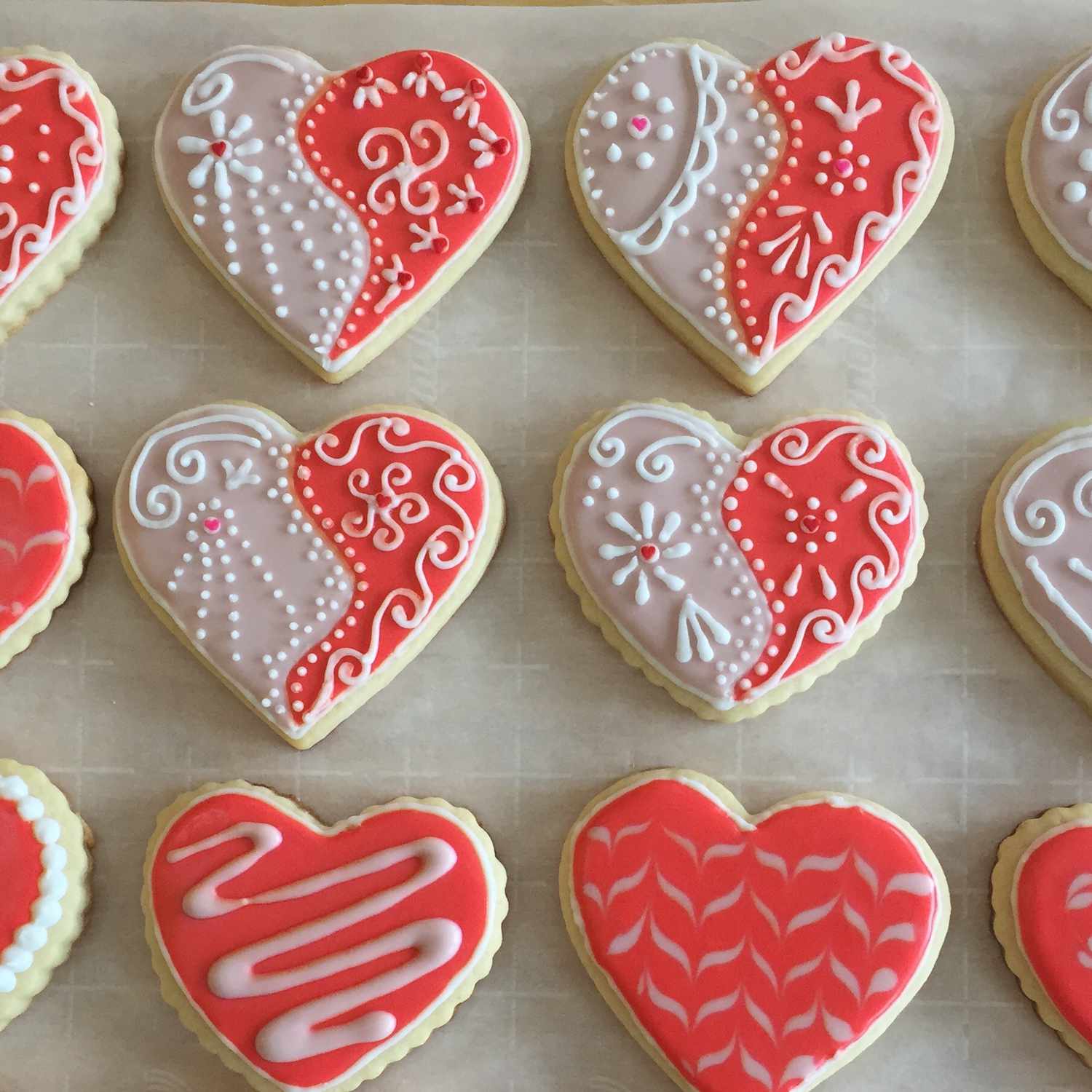 Valentine heart-shaped cookies decorated with white and red icing and intricate piped designs