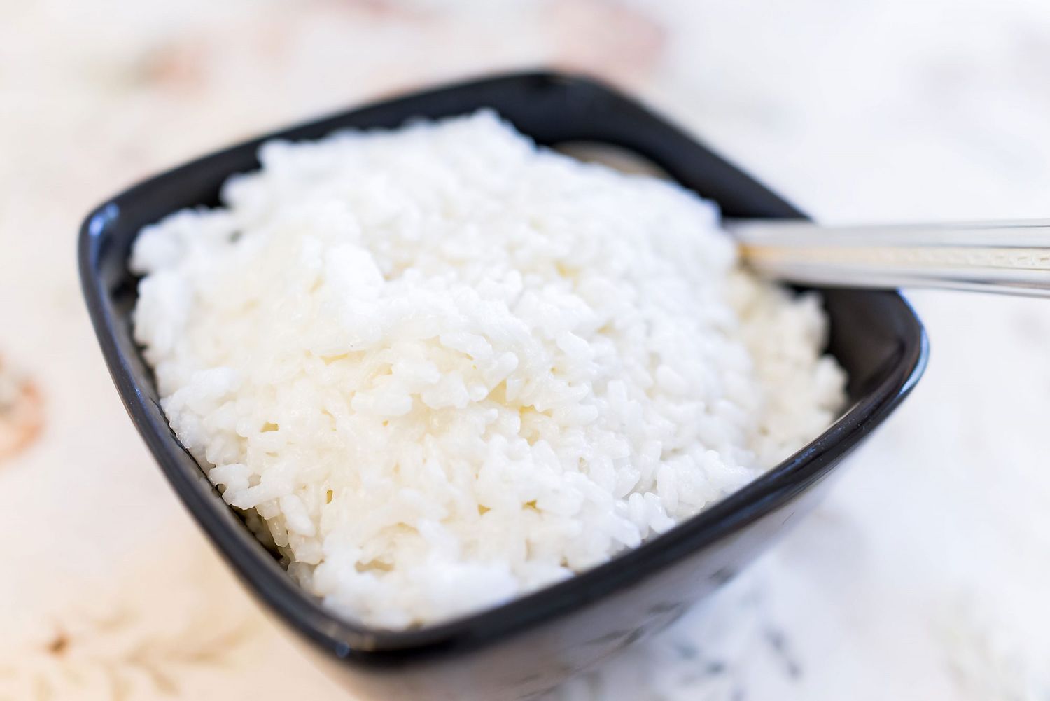 white jasmine rice in black square bowl with fork