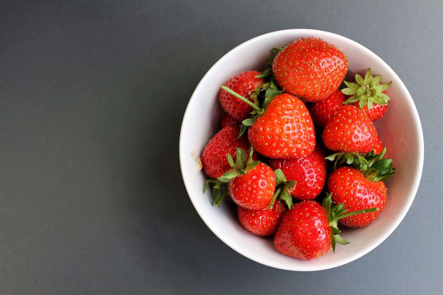 Directly Above View Of Strawberries In Bowl On Gray Background