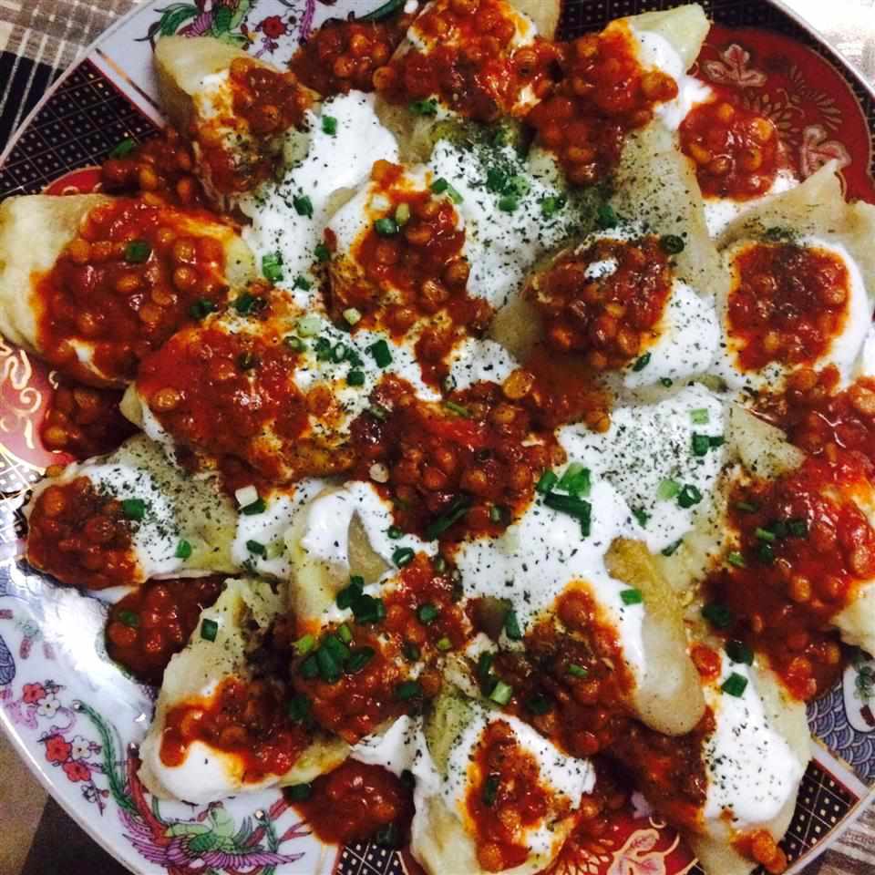 beef ravioli topped with beef, yogurt sauce, and red sauce