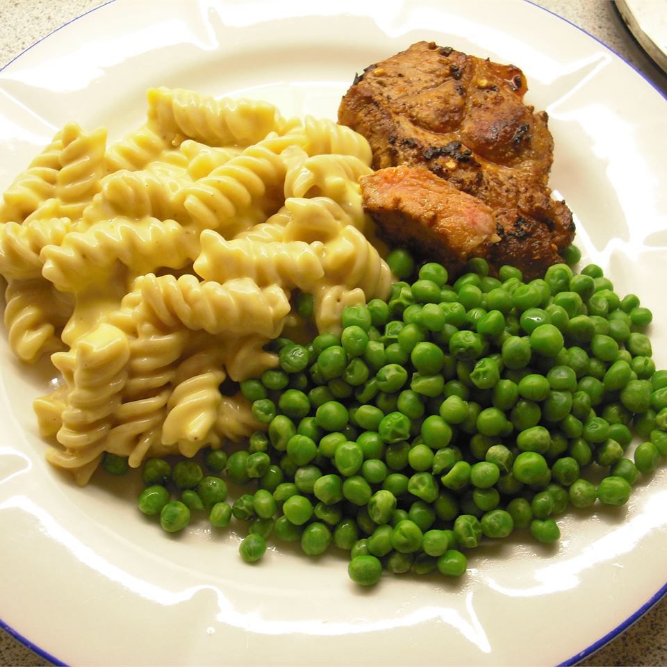 Creamy Macaroni and Cheese on a plate with peas and steak