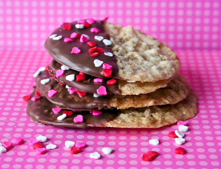 lace cookies half-dipped in chocolate with red, white, and pink heart sprinkles for Valentine's Day