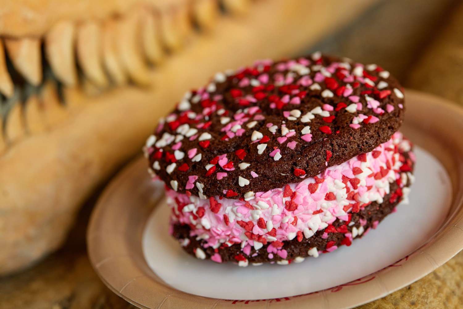 Disney-themed ice cream sandwich with chocolate cookies and pink ice cream decorated with red, pink, and white mini heart candies