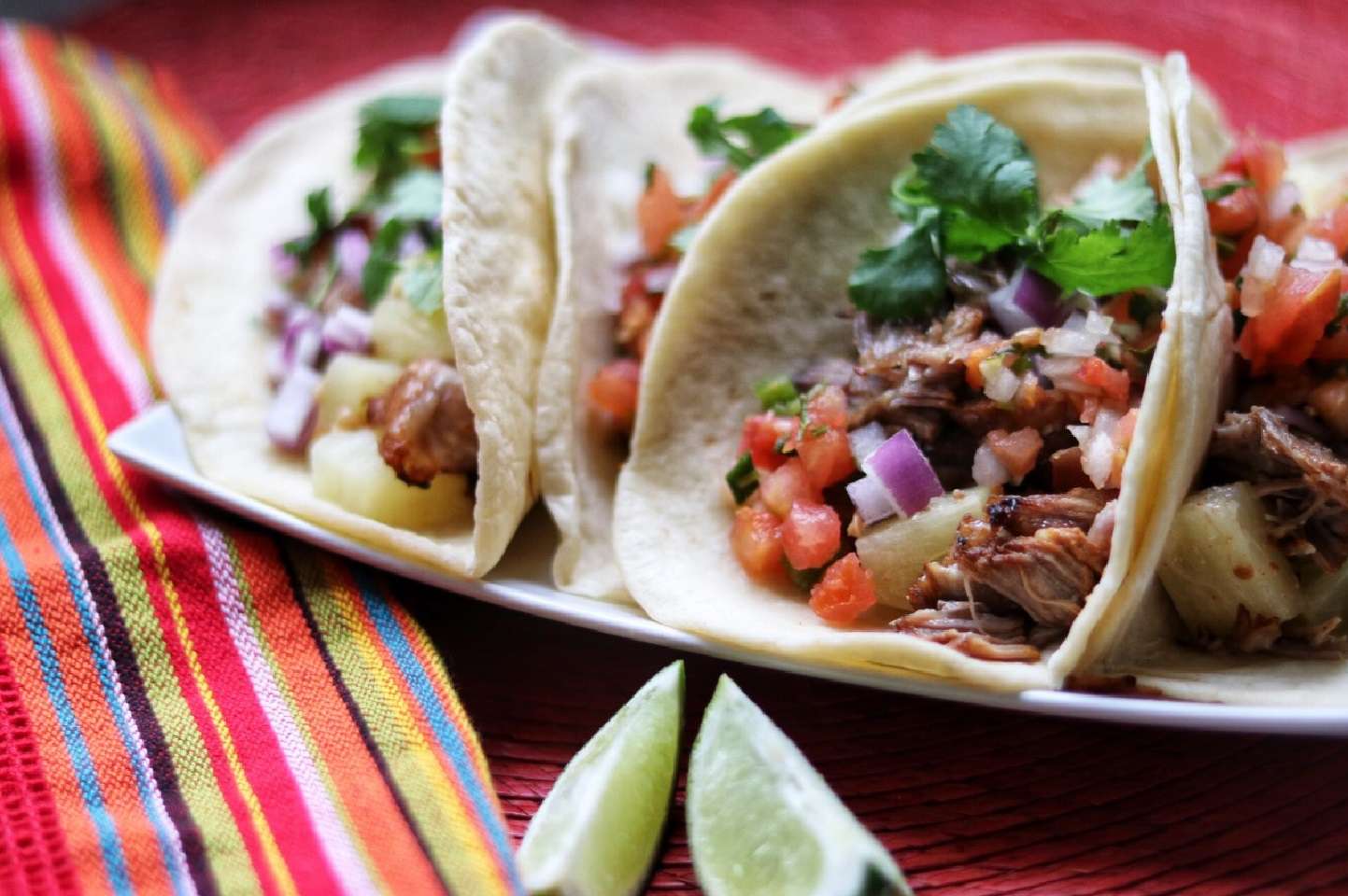 flour tortillas tacos with shredded pork, pico, and cilantro on plate