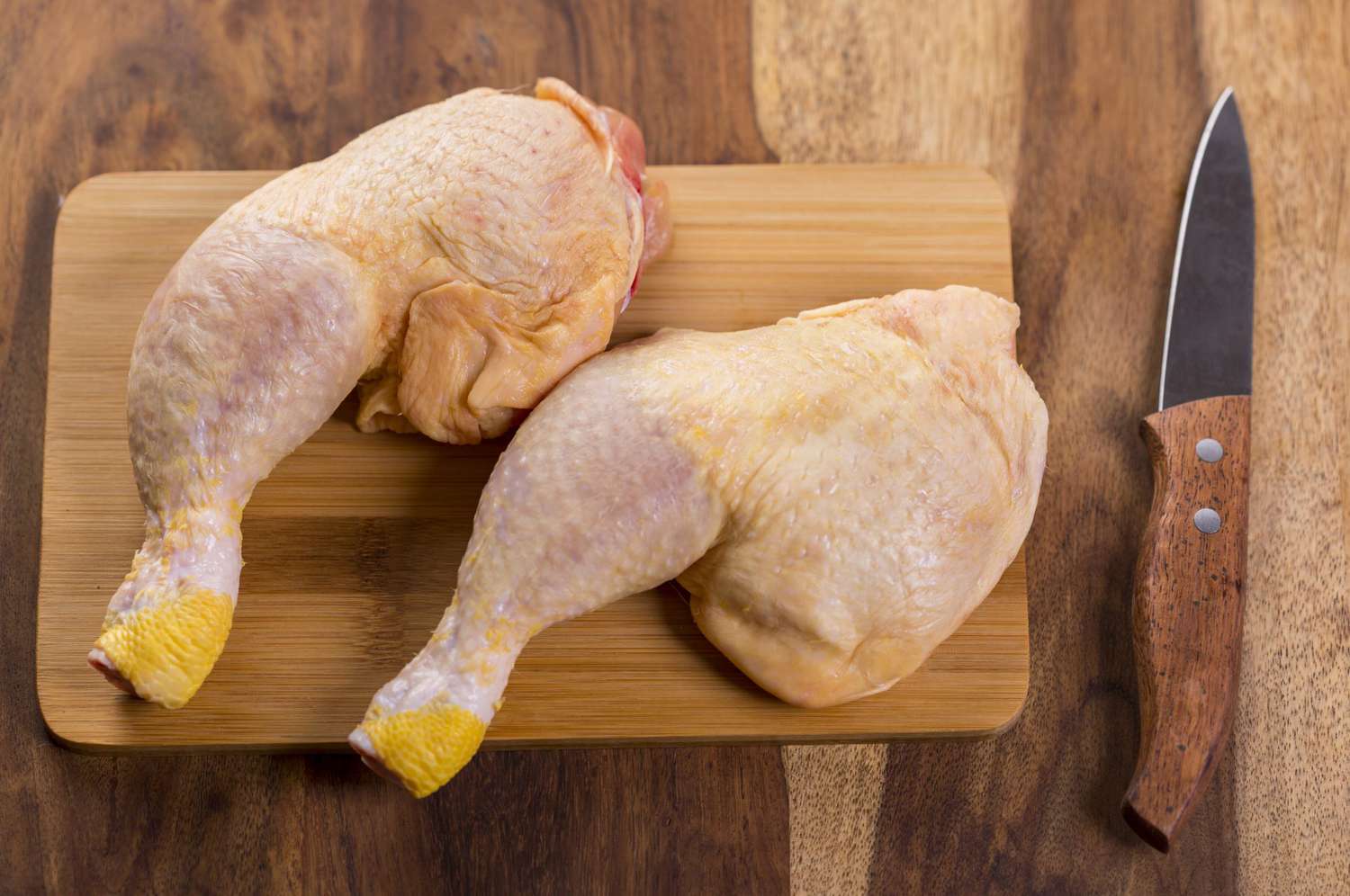 Two chicken legs on chopping board