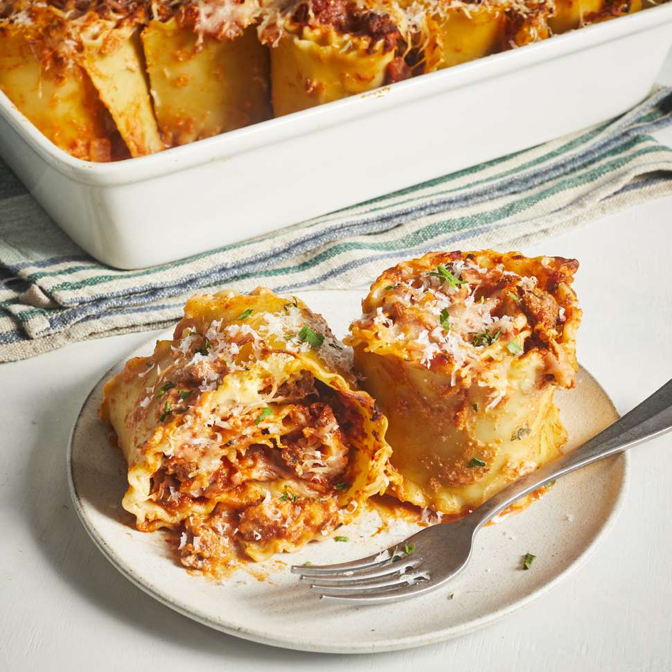 Two Lasagna Roll Ups plated with the casserole dish in background
