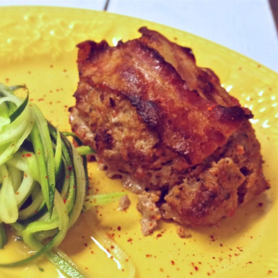 mini meatloaf topped with bacon served with zucchini spirals on a yellow plate