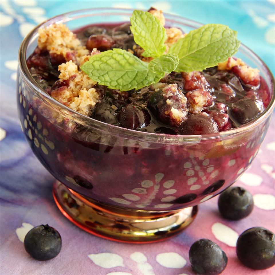 berry crumble in glass dish with loose berries around