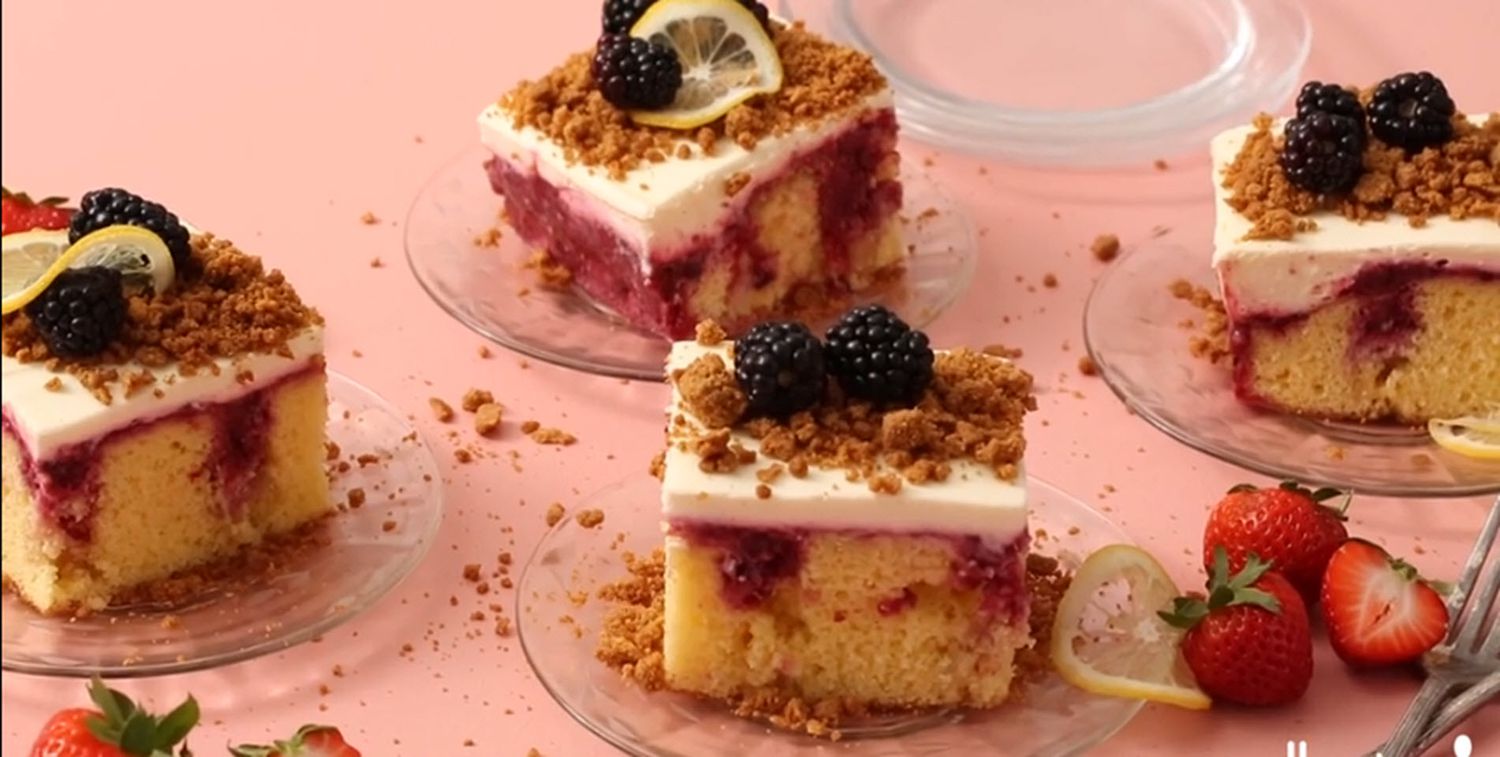 squares of triple berry cheesecake poke cake on glass plates