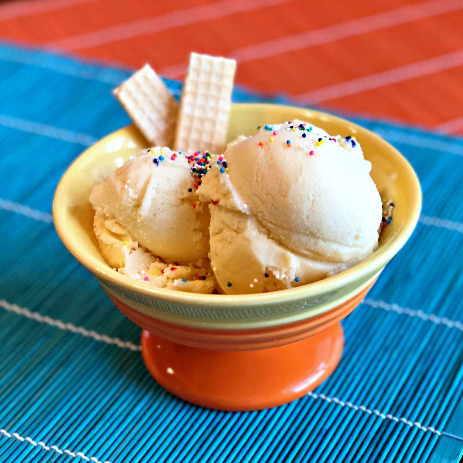 a bowl of vanilla ice cream with sprinkles and wafers