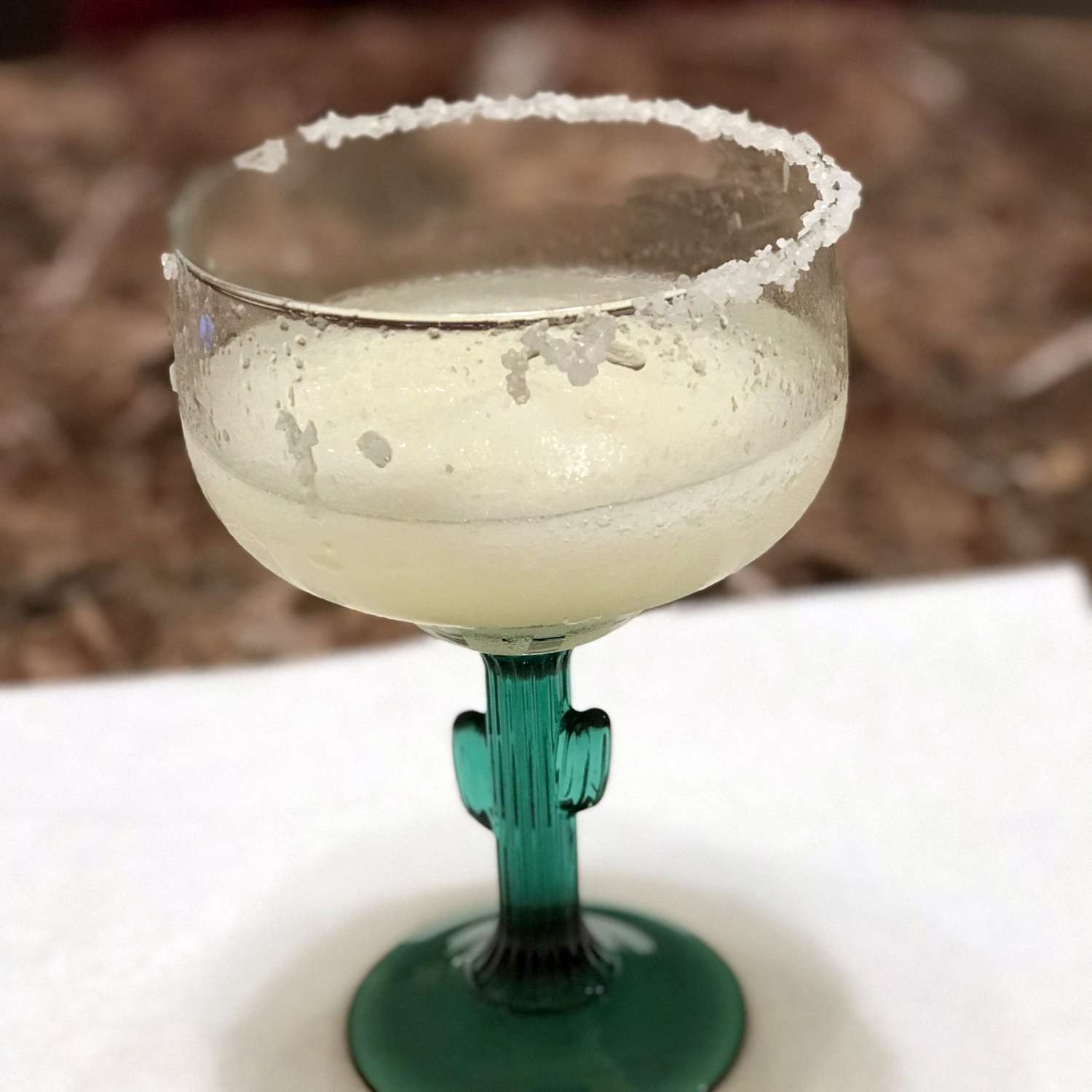 a margarita with a salted rim served in a fun cocktail glass with a saguaro cactus as the stem