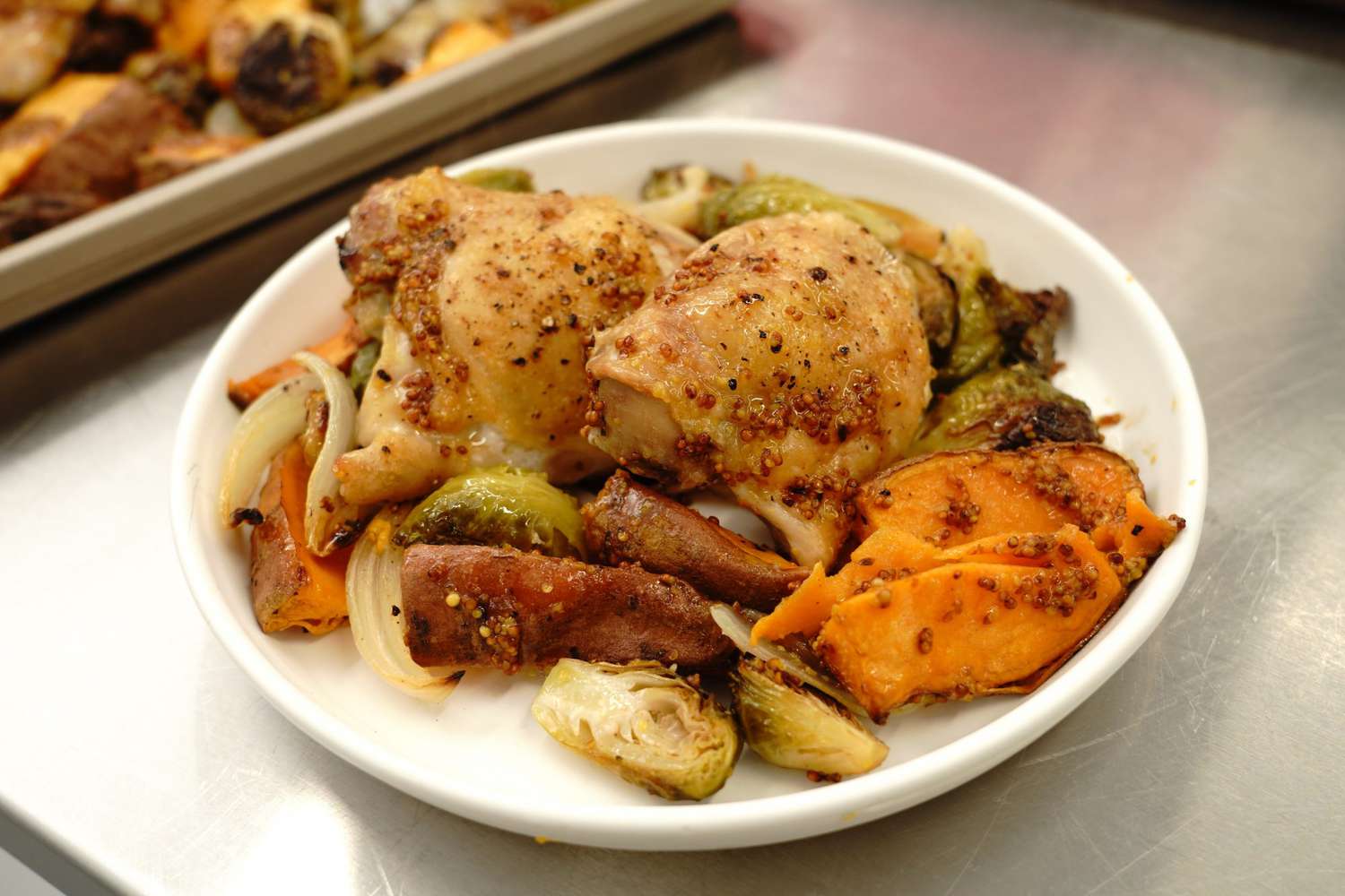 sheet pan chicken and veggies with mustard vinaigrette recipe served with Brussels sprouts, onions, and sweet potatoes