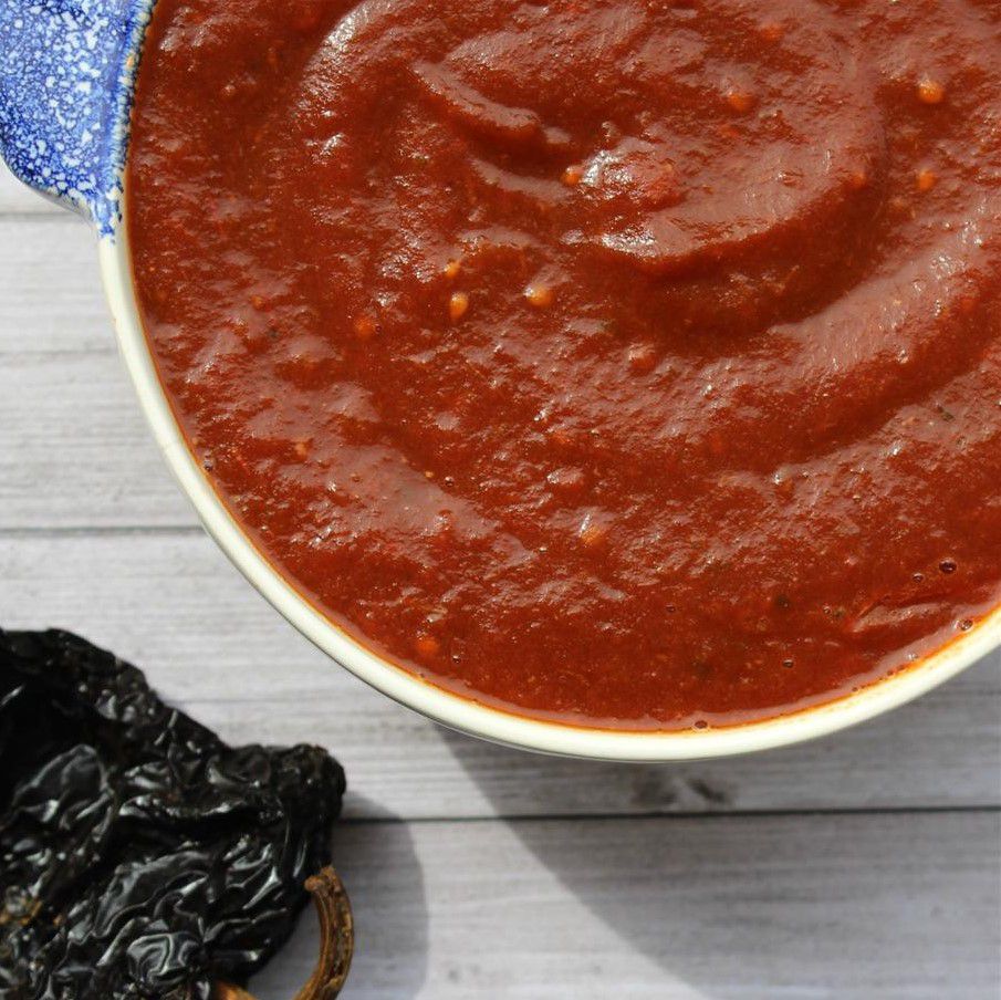 bowl of enchilada sauce with dried chile on the side