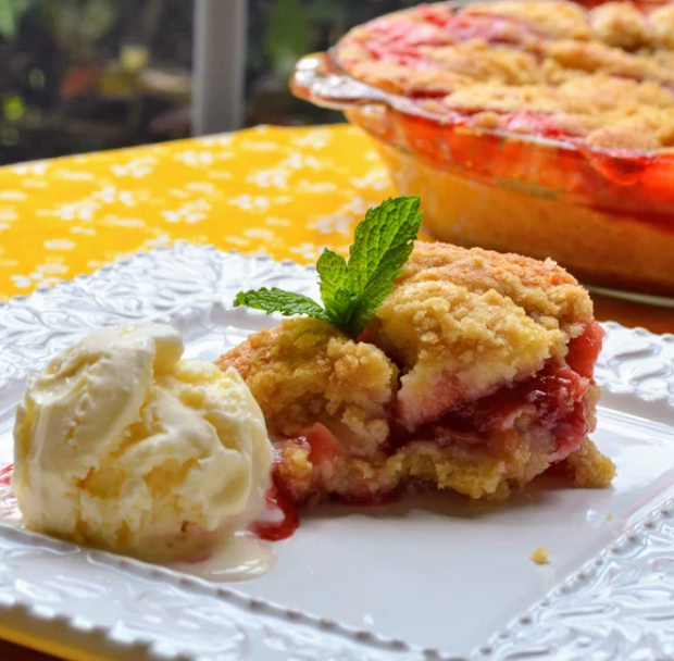 a serving of strawberry-rhubarb crisp with a scoop of vanilla ice cream on a plate