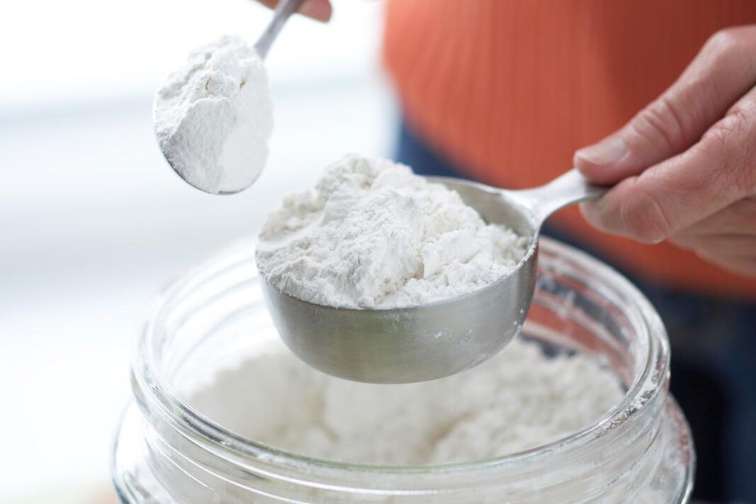 measuring flour by spooning it from a jar into a measuring cup