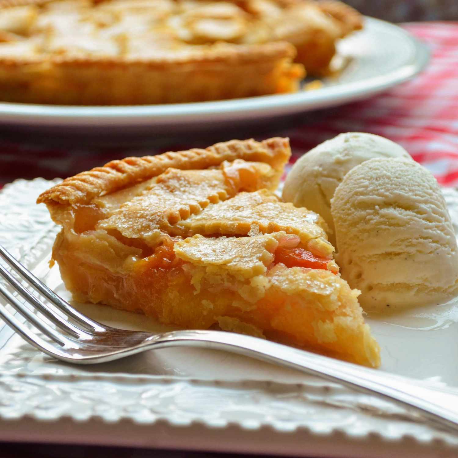 slice of chef john's peach pie served with ice cream on the side