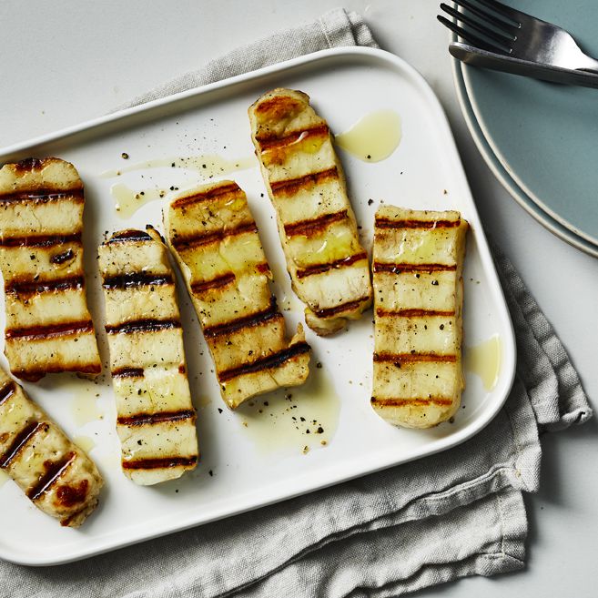 a tray of grilled halloumi that has been drizzled with olive oil and topped with fresh cracked black pepper