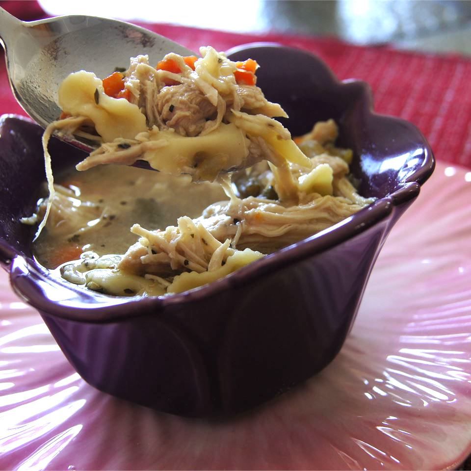 chicken noodle soup in a purple bowl with a spoon