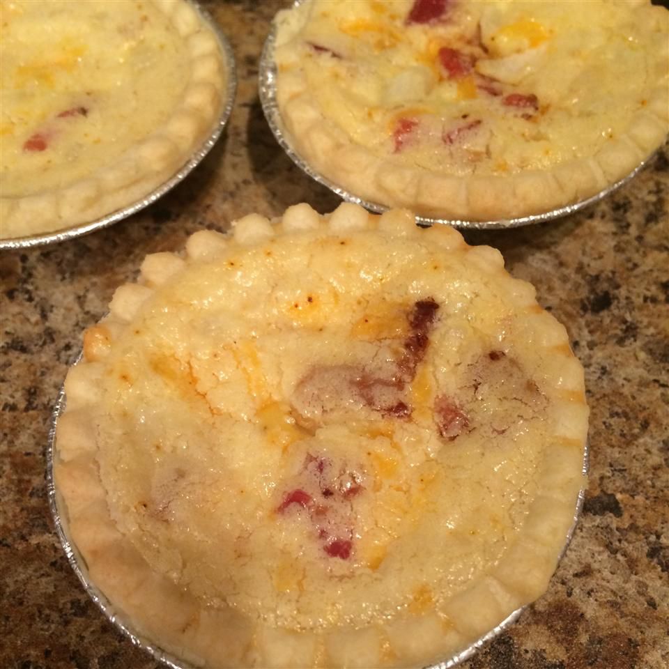 three mini quiches with cheese and bacon in mini pie crusts with foil