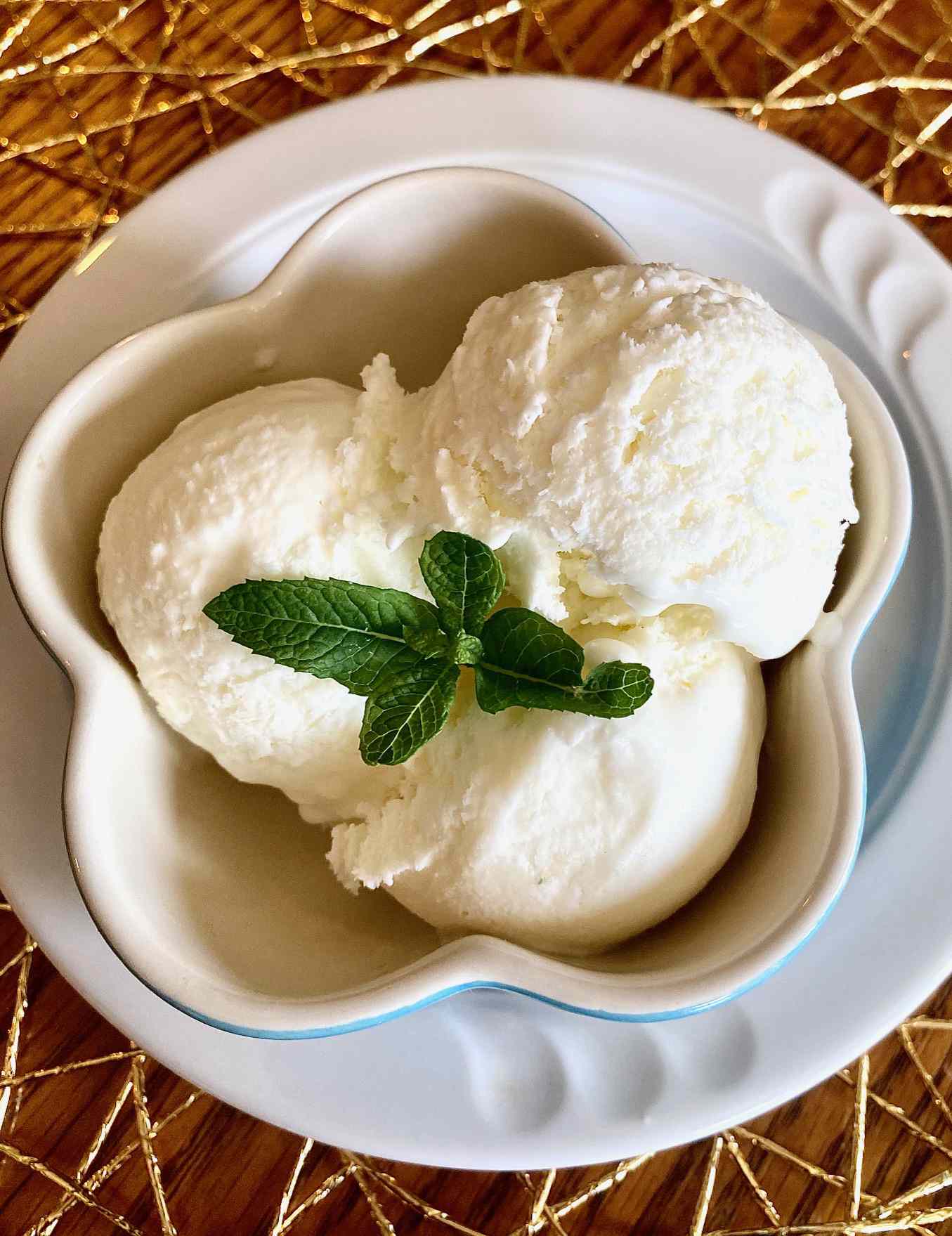 top-down view of three scoops of pale yellow ice cream garnished with fresh mint leaves