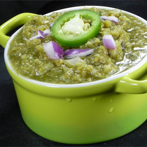 a green dish with salsa verde and a slice of fresh jalapeno on top