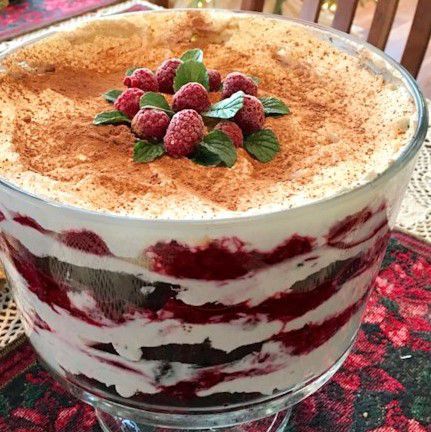 a raspberry trifle garnished with frozen raspberries and mint leaves