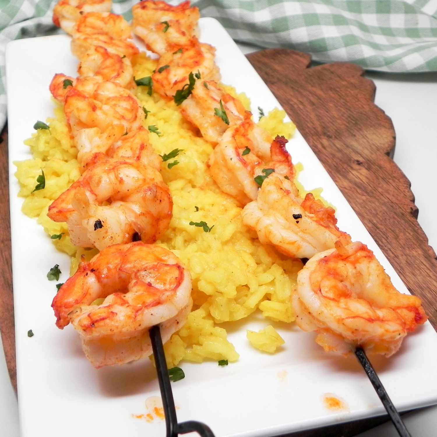 grilled shrimp on skewers over yellow rice on a white plate