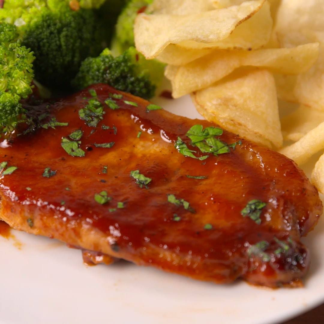 pork chops smothered in bbq sauce on a plate with chips and vegetable