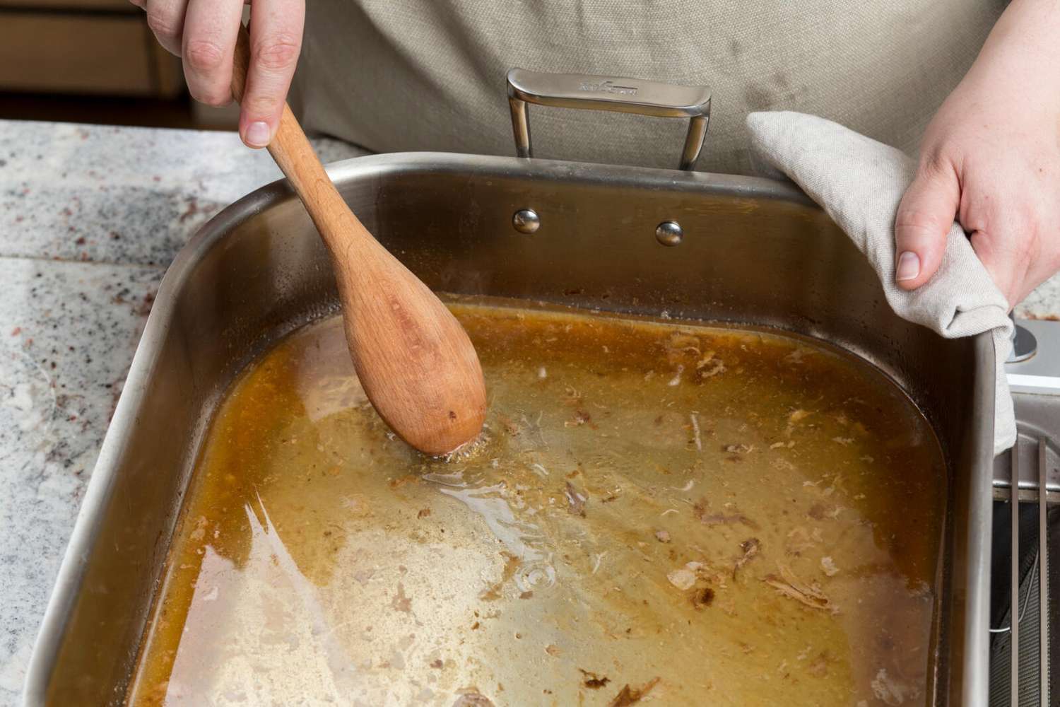 pan drippings in roasting pan with wooden spoon