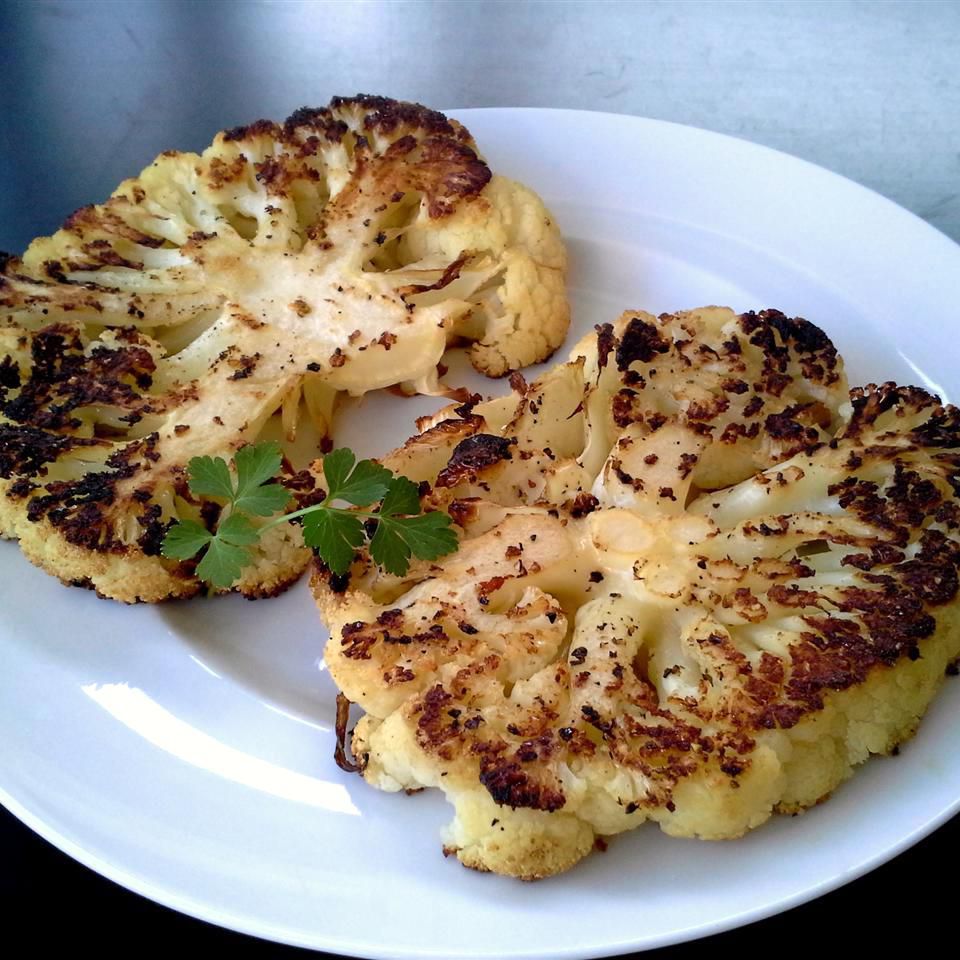 two roasted cauliflower steaks on a white plate