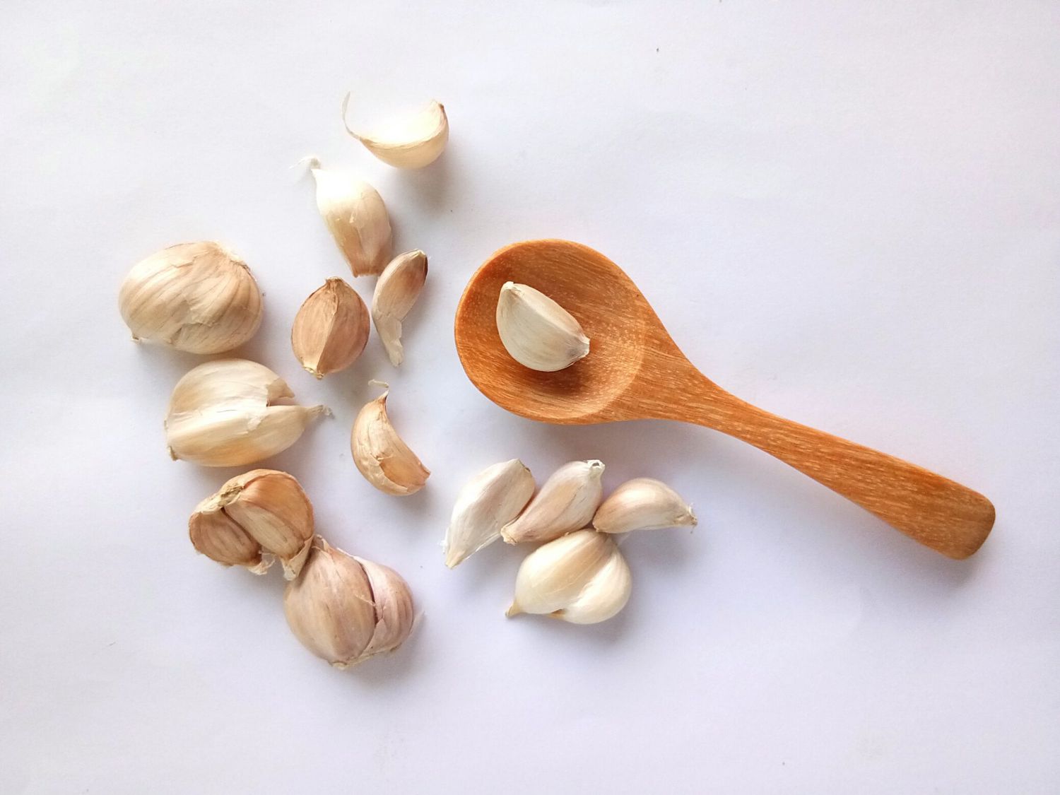 Close-Up Of Garlic With Wooden Spoon Over White Background
