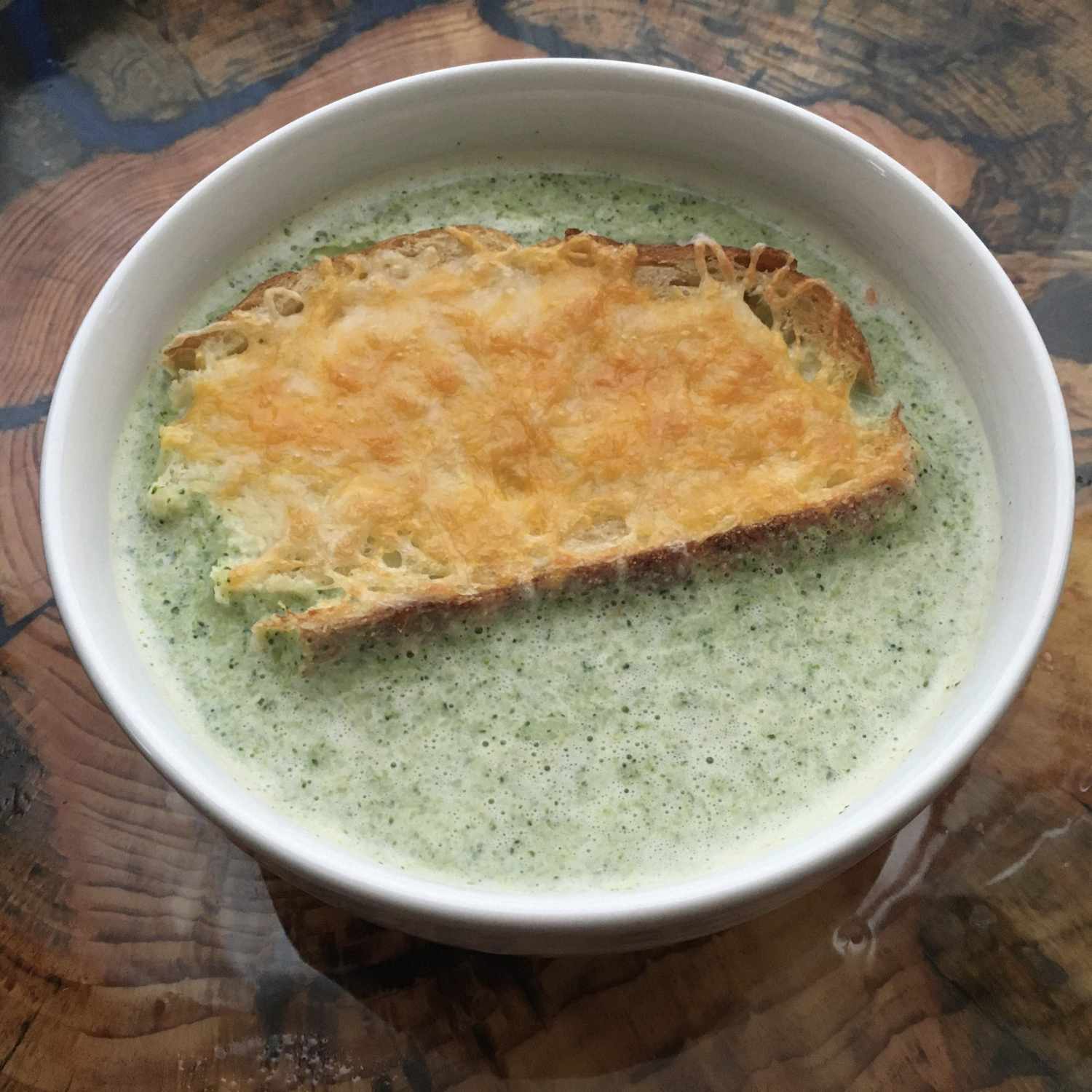 Broccoli Soup in a white bowl with a slice of cheese toast