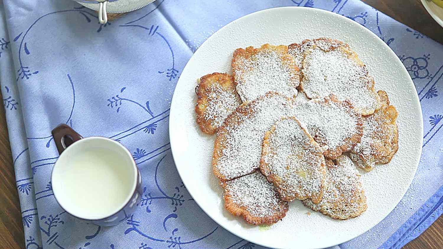 small pancakes with powdered sugar on blue plate
