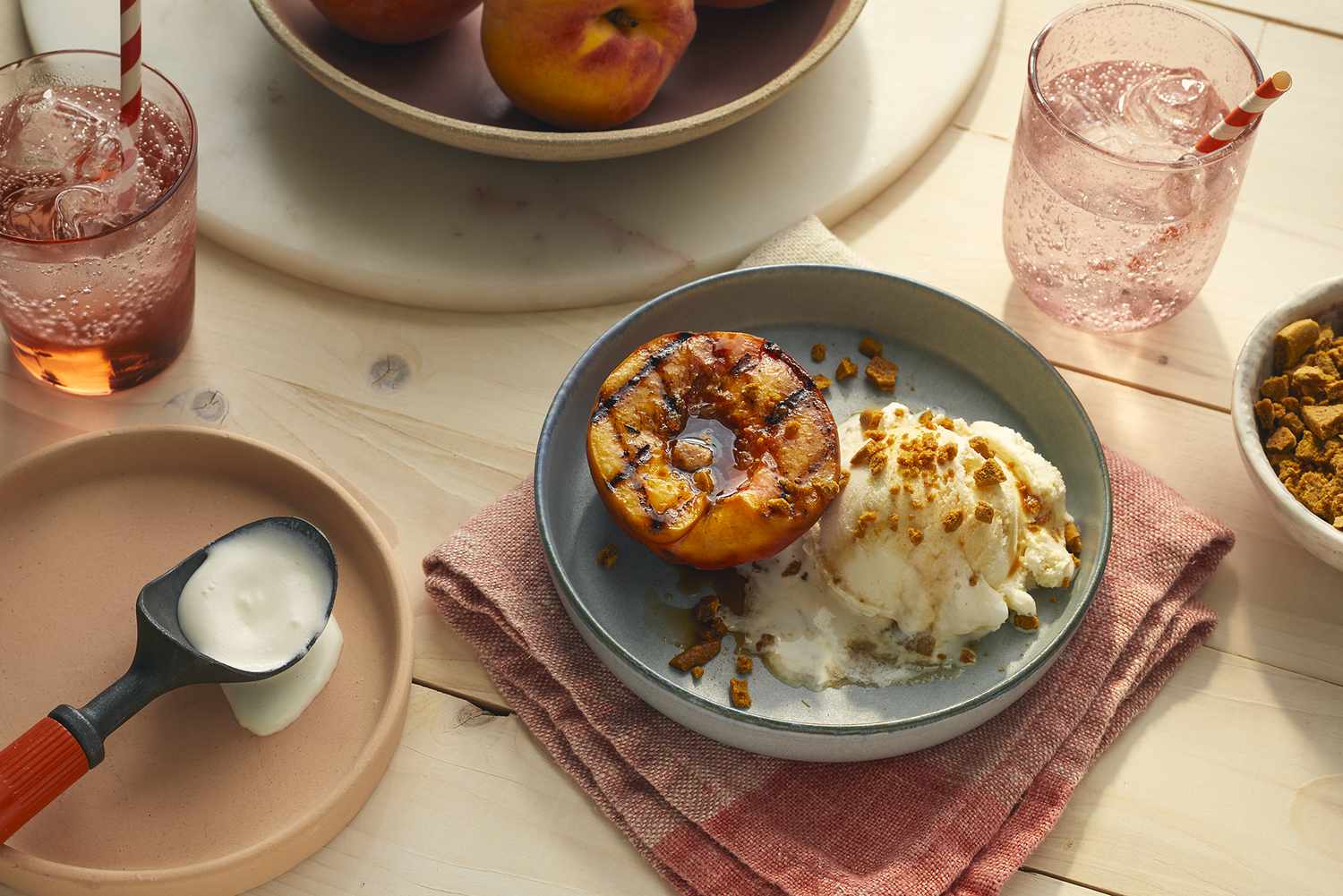 A beautifully grilled peach served with a melting scoop of vanilla ice cream and crumbled gingersnap cookies