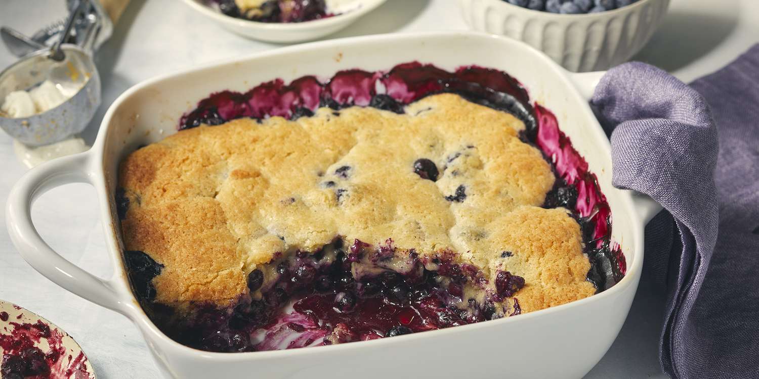 best ever blueberry cobbler scooped to reveal the bright blueberries beneath the golden-brown crust.