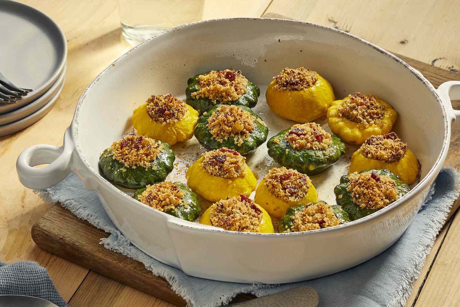 An oval casserole dish with several yellow and green stuffed patty pan squash.