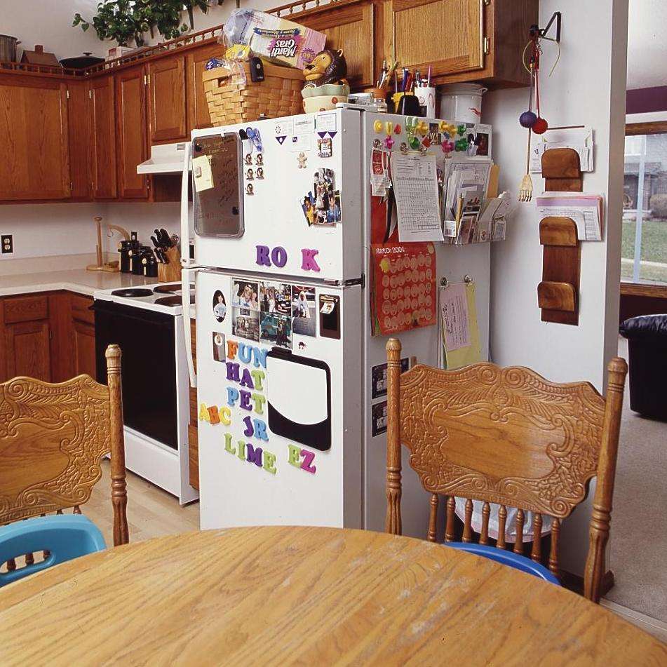 kitchen with wooden table and chairs, white refrigerator with photos and magnets