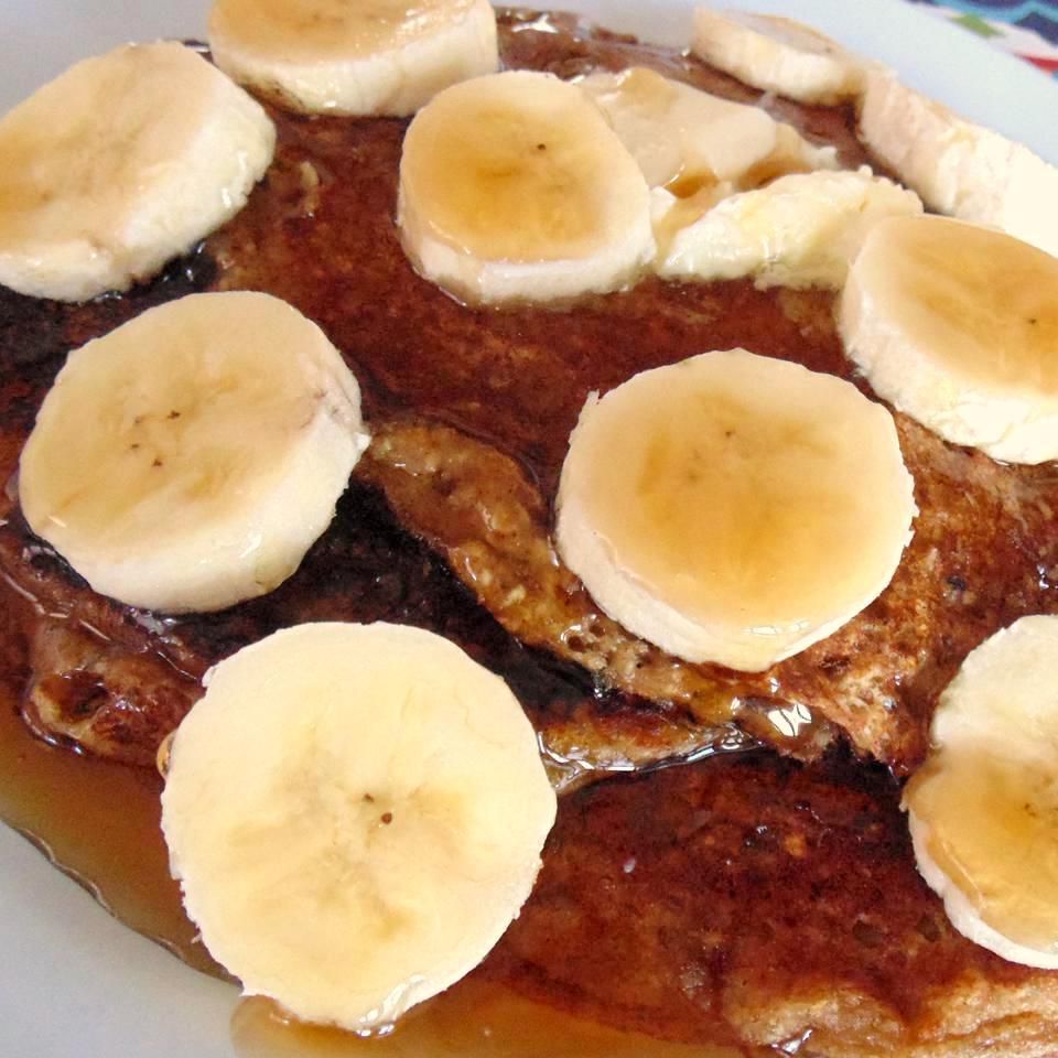 stack of pancakes with banana slices and syrup on top