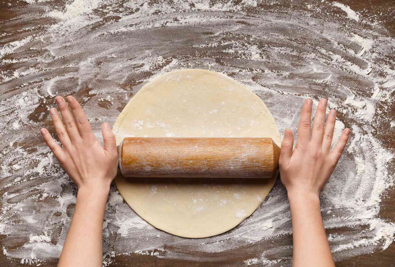 Preparation of pastry. Woman rolling dough, top view