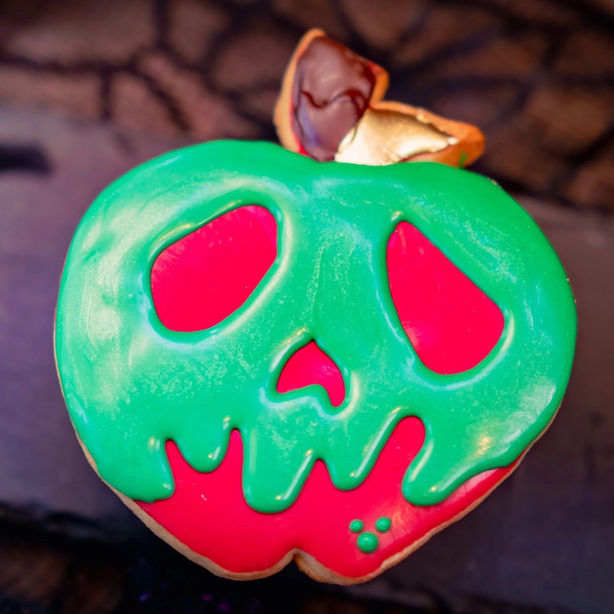 apple shaped sugar cookie decorated with green and red icing to make a scary face for a Disney Halloween treat